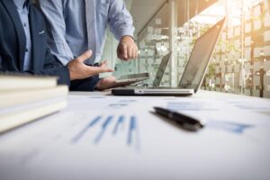 Mesa com notebooks e duas mão apontando para as telas simulando como abrir uma empresa